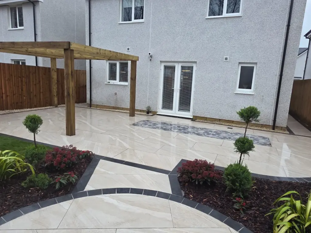 Porcelain patio with pergola and tile inlay by RS Bespoke Gardens